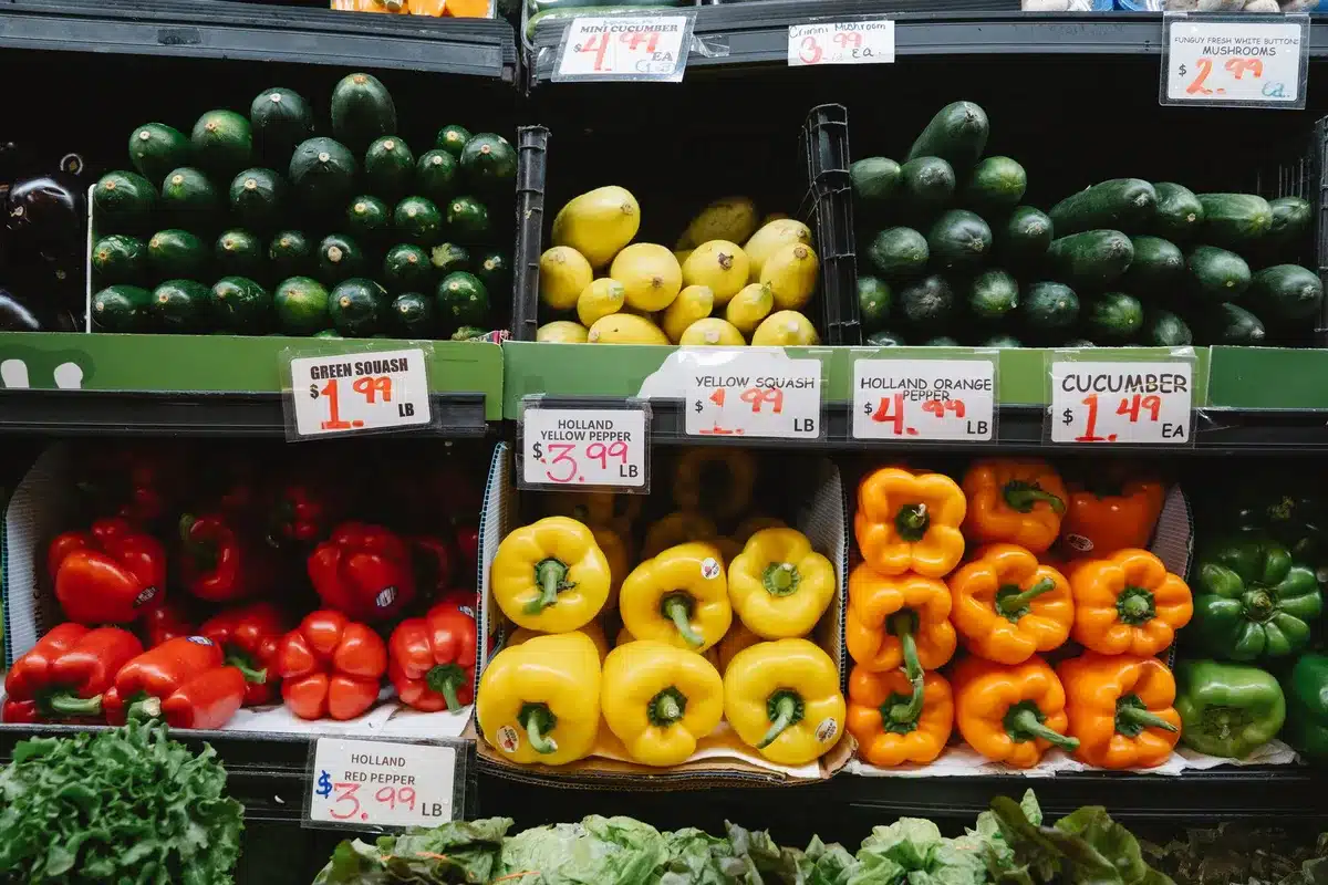 Fresh produce market display with lettuce and salad greens on shelves, grocery store setting, customers browsing, everyday food shopping scene