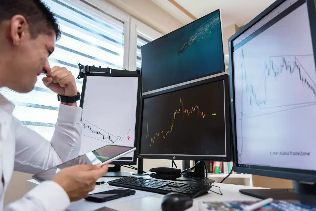 A laptop screen displaying financial charts and graphs with red downward arrows, a hand scrolling through data, dim office lighting, abstract representation of market concerns and investor skepticism