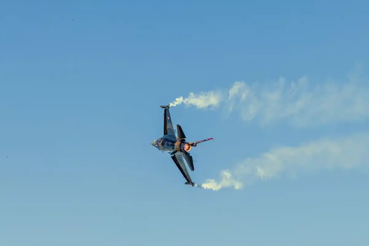 A Rafale fighter jet in flight against a clear sky, wings at full span, afterburners glowing, sleek silhouette showing the aircraft's advanced aerodynamic design