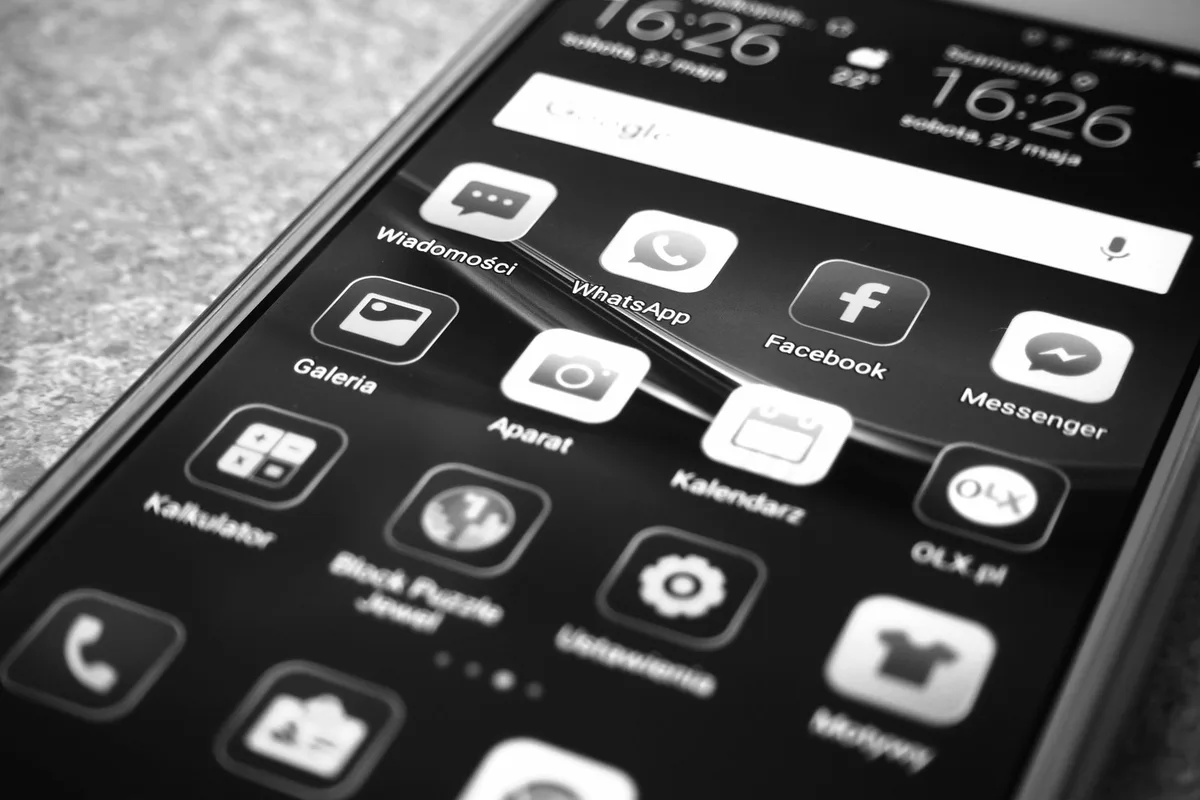 A Truth Social post on a smartphone screen, glowing against a dark background, text visible but slightly blurred, a single hand holding the device