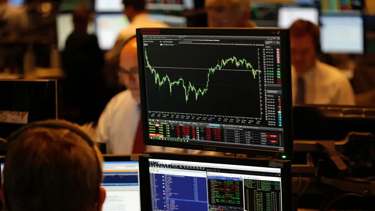 Stock market screen displaying green candlestick chart with rising trend line, multiple monitors showing financial data and ticker symbols, trading floor atmosphere | stock market rally