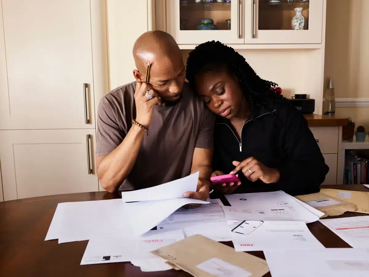 A family reviewing bills and receipts at a kitchen table, papers spread out, a calculator visible.