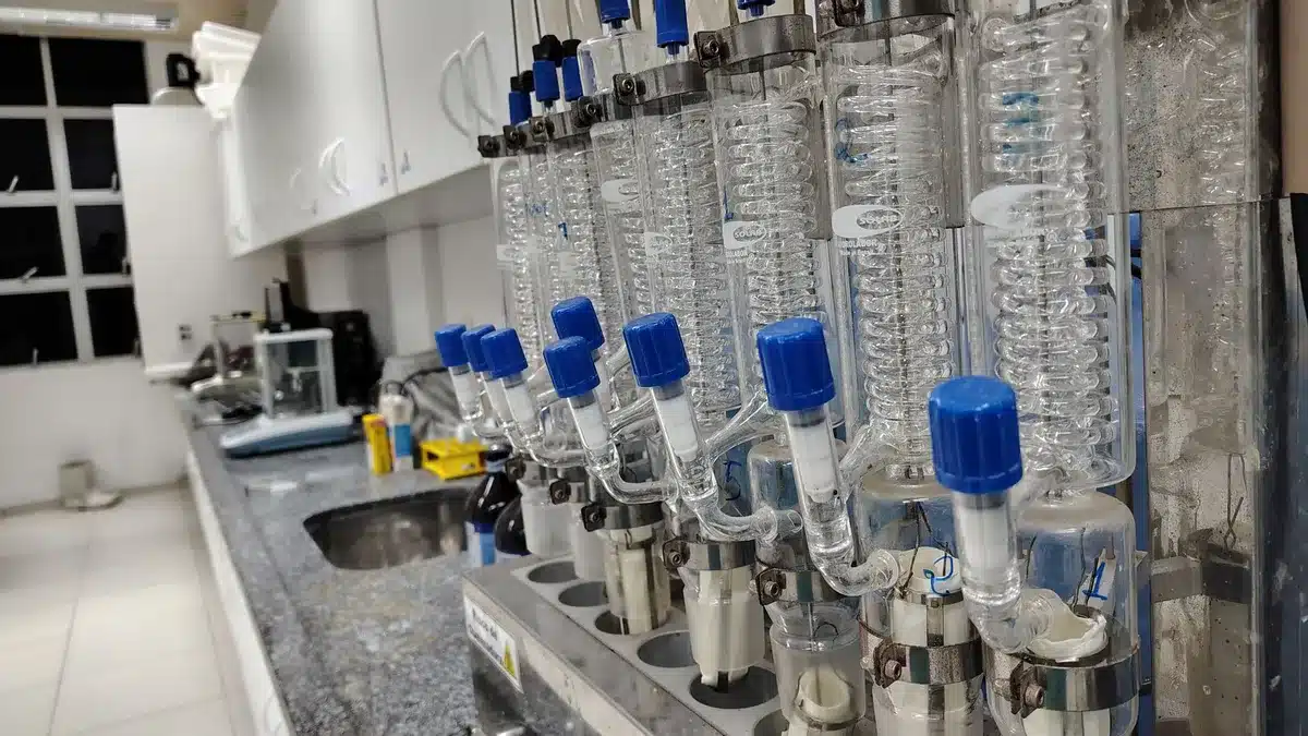 A modern research laboratory with microscopes and scientific equipment on clean workbenches, soft blue-white lighting illuminating glass containers and digital displays