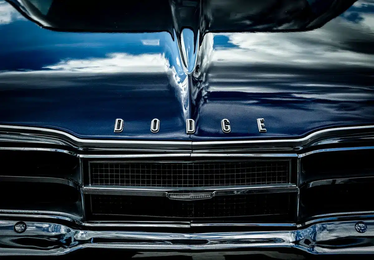 A muscular Dodge Charger Super Bee in vibrant Sucker Punch yellow with gloss-black hood decals and aggressive styling cues, parked on a wide-open drag strip under bright sunlight