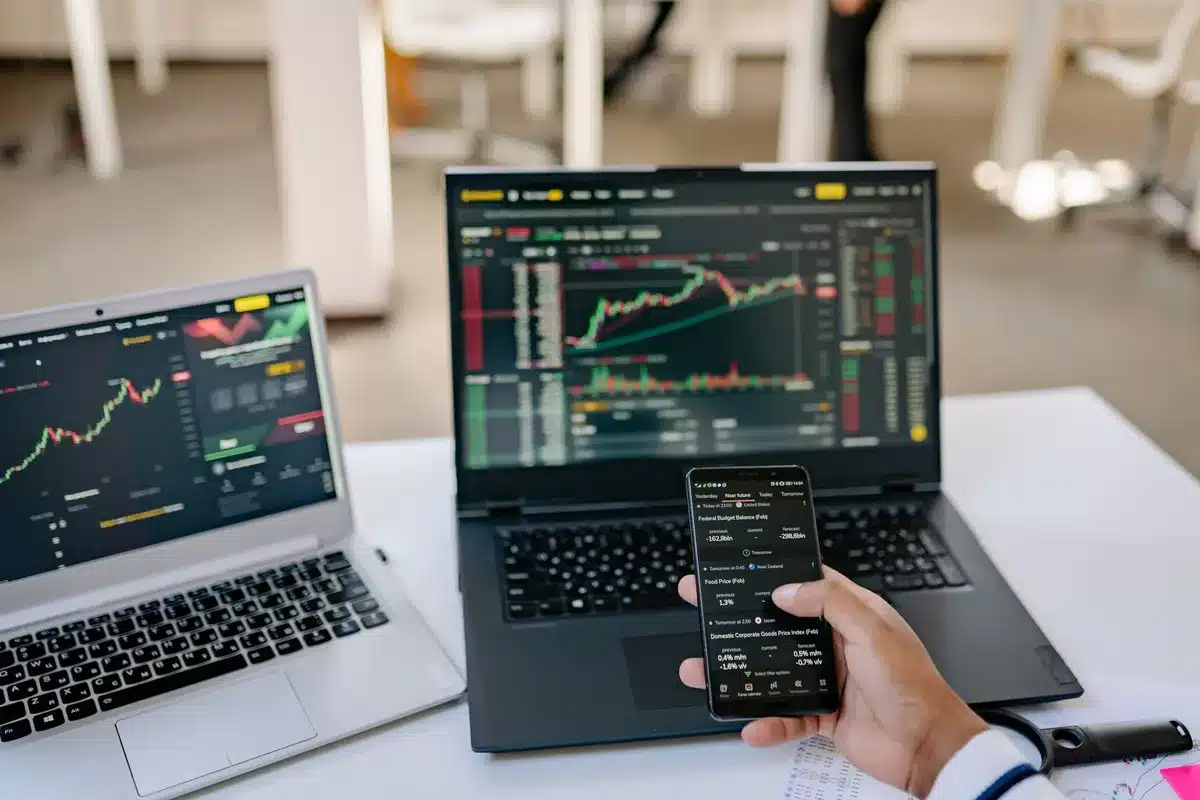 A stock market trading screen displaying currency indices and price charts in real-time, with downward-trending arrows and numerical data visible, muted colors