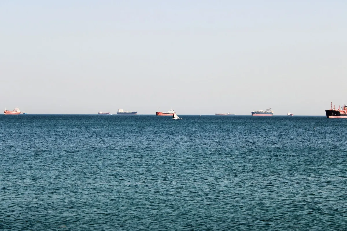 A world map highlighting the Strait of Hormuz with shipping lanes marked, oil tankers visible in the waterway, geopolitical tension indicated by visual markers
