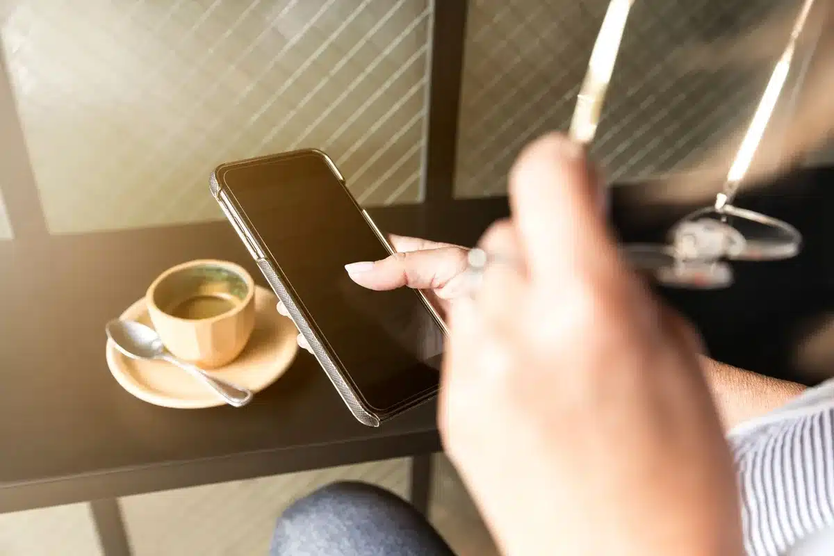 A glowing coffee cup on a dark counter, steam rising, a smartphone displaying the Dunkin' app interface blurred beside it, warm ambient lighting highlighting the drink