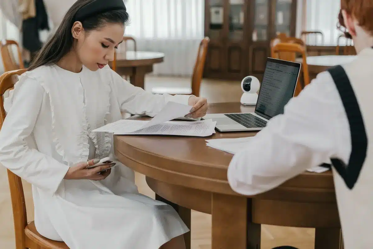 An anonymous borrower reviewing loan documents on a desk, papers and statements spread out, focused expression, indoor office setting with soft natural light