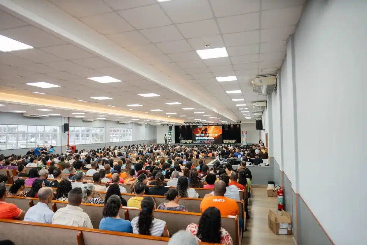 A split-screen showing an empty auditorium on one side and a diverse group of silhouettes facing a stage on the other, representing dialogue and reconciliation between political factions.