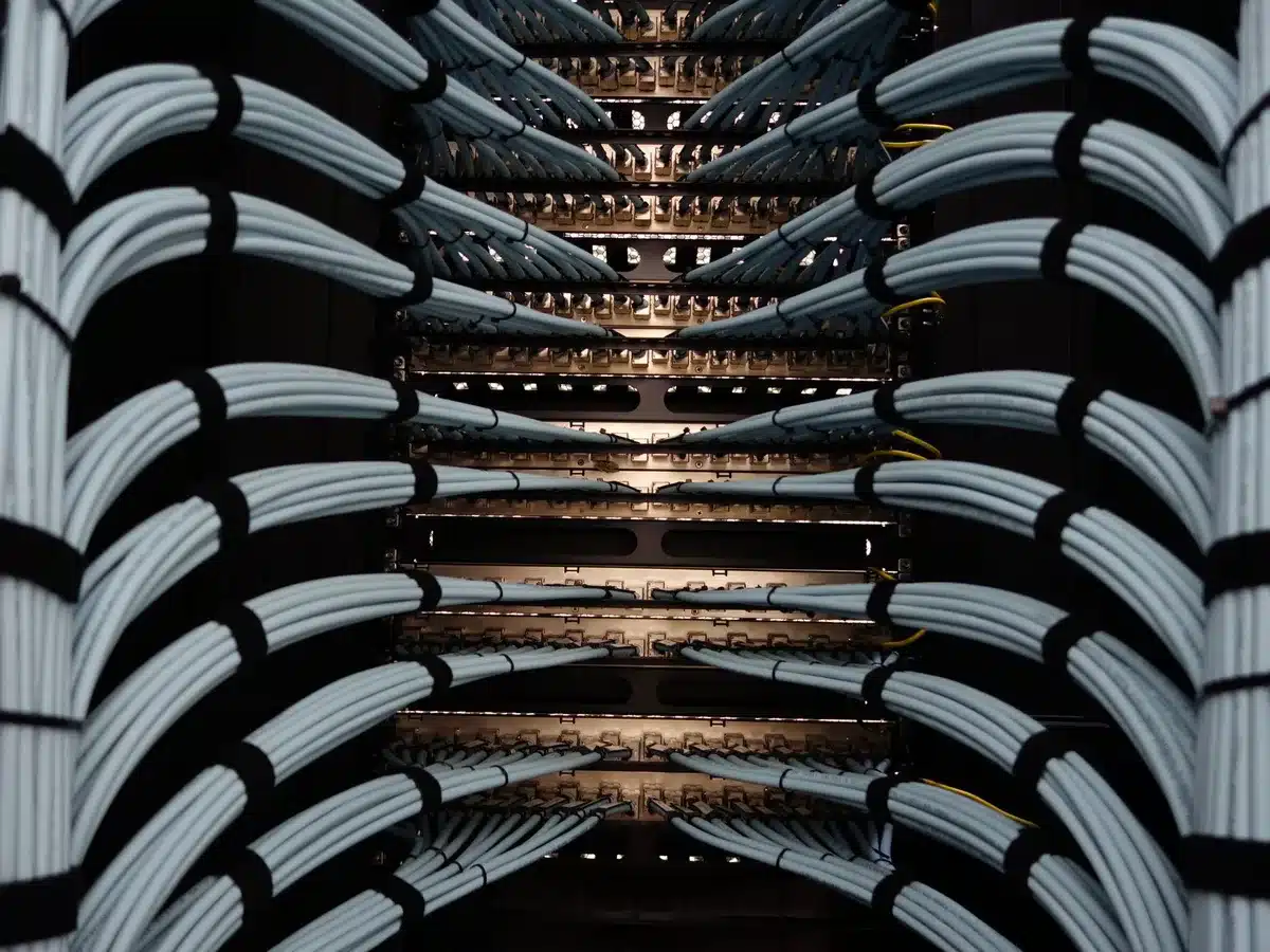 Towering server racks illuminated with blue and white light, stretching into darkness, cooling systems humming in background, cables organized in geometric patterns