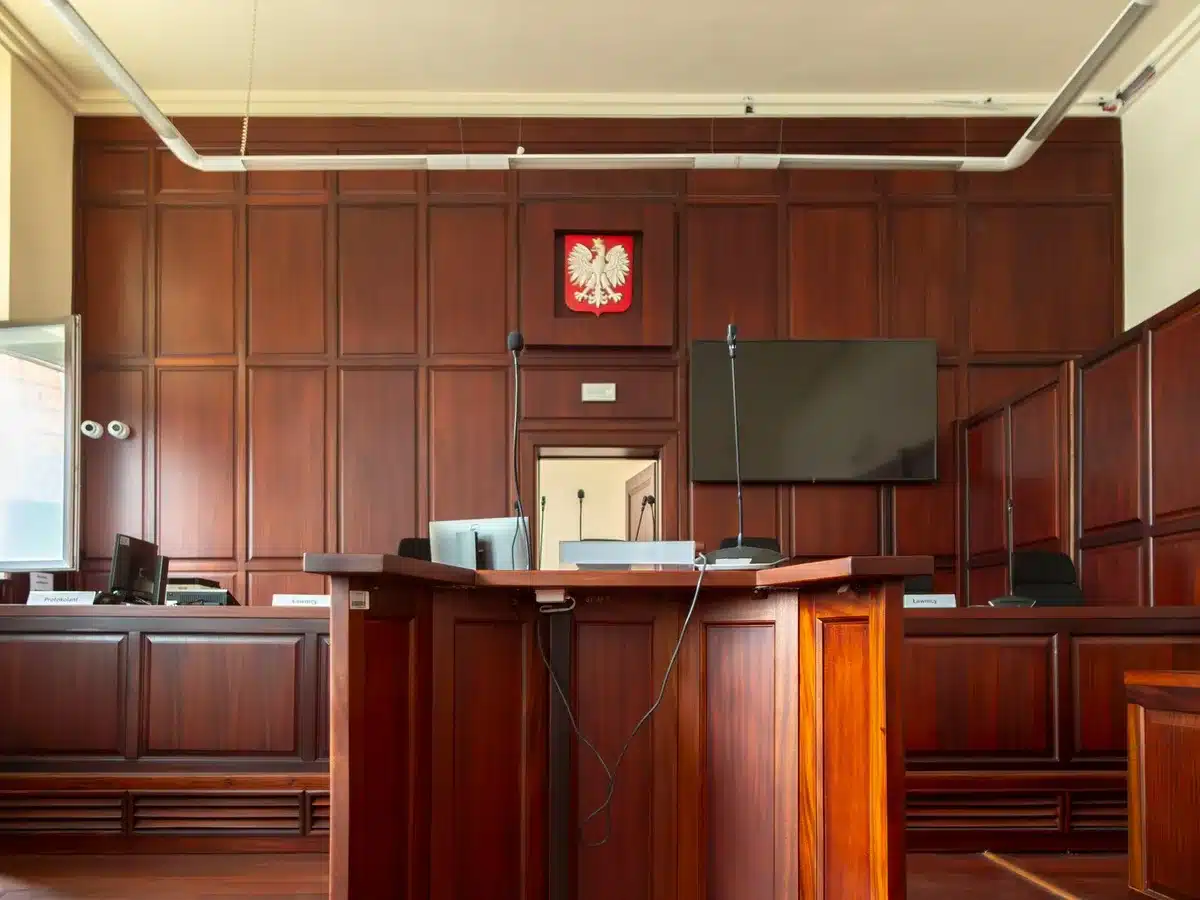 Gavel on judge's bench in dim courtroom light, legal documents stacked nearby, scales of justice blurred in background, formal legal setting