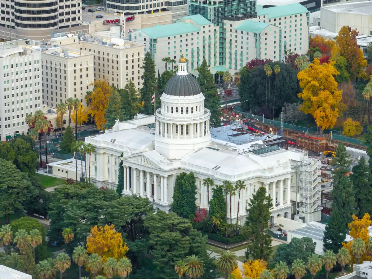 A state capitol building exterior at dusk with flags, symbolizing state government authority and jurisdiction