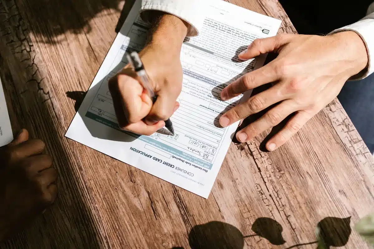 Student loan documents spread on a table with a calculator, pen, and financial statements, neutral overhead lighting