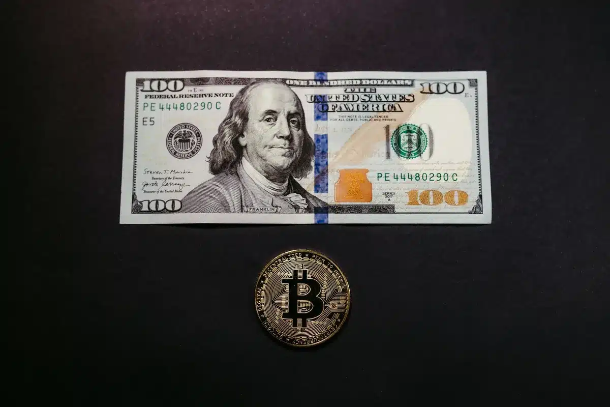 A minimalist scene showing a single Bitcoin coin catching light against a dark background, surrounded by blurred institutional buildings and glass facades, a subtle upward arrow shape formed by light rays, cool institutional color palette