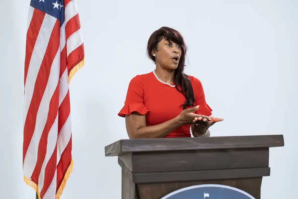 A press conference podium with microphones in a government building, empty of people, harsh fluorescent light casting sharp shadows on the wood surface, tension in the stillness.