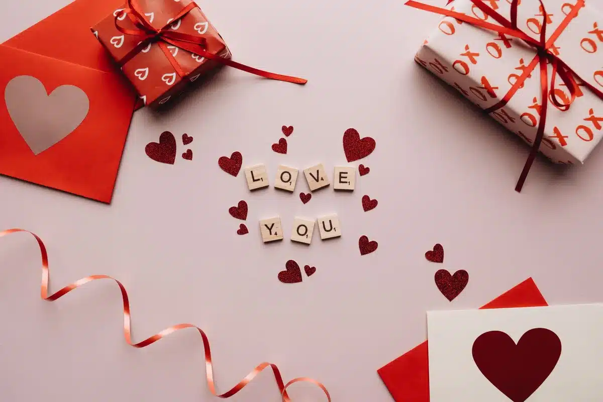 A colorful array of handwritten greeting cards and friendship bracelets arranged on a wooden table, with fresh flowers and small gift boxes nearby, symbolizing connection and appreciation