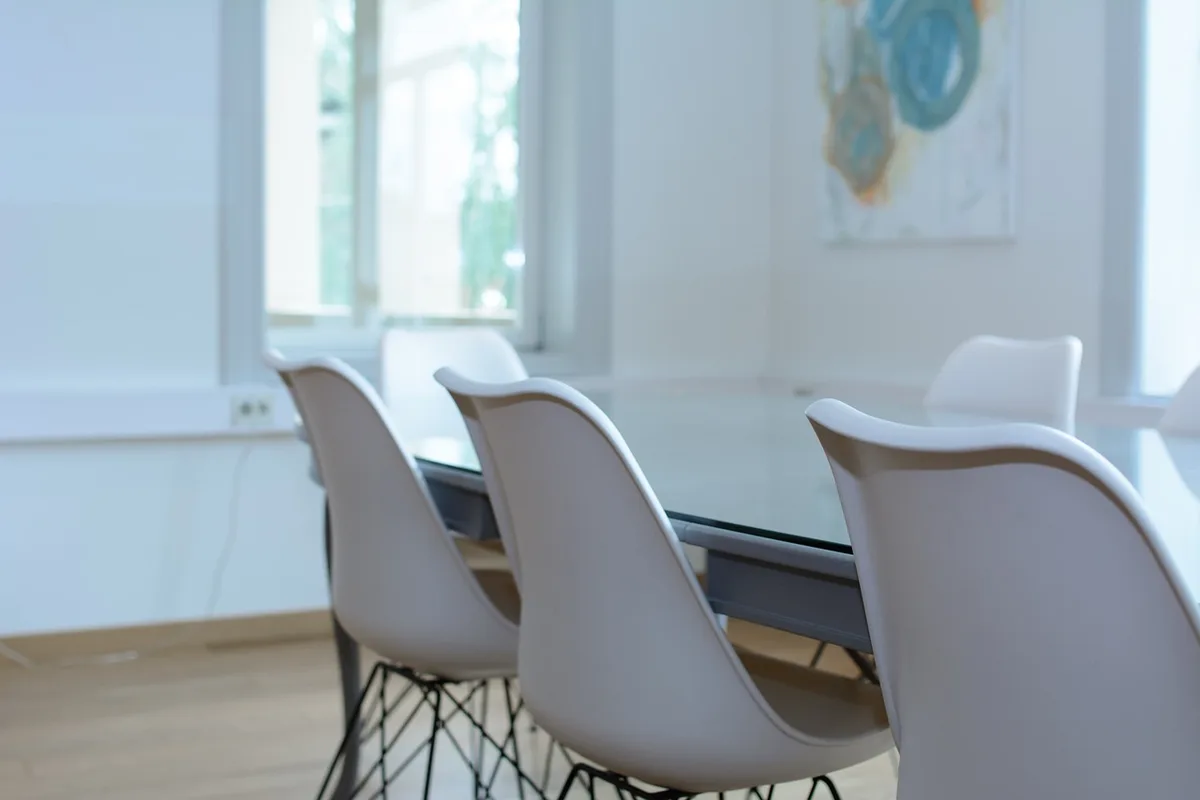 An empty conference room with chairs arranged around a table, a single microphone on the podium, no people present