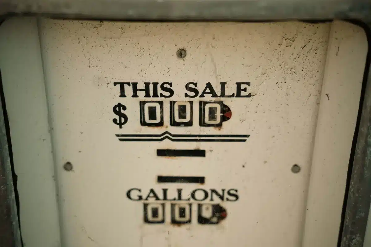 A gas pump display showing prices declining, with a digital screen reflecting downward numbers, morning light casting shadows across the pump, indicating a shift in consumer costs