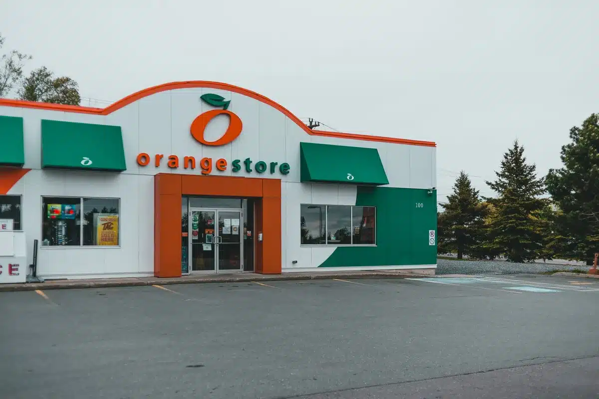 An empty, dimly lit retail storefront or shopping area with closed signs and minimal foot traffic, fluorescent lighting overhead, suggesting economic slowdown.