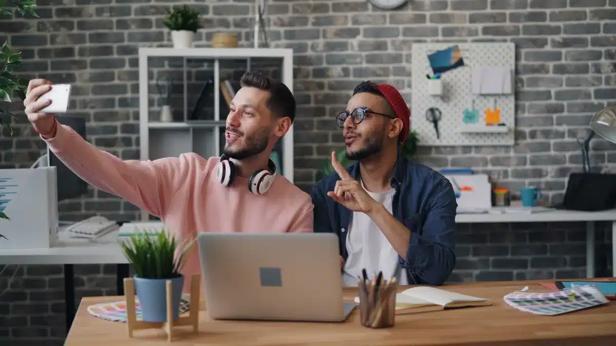 A modern office space with diverse young professionals collaborating at desks and standing by windows, natural light streaming in, laptops and notepads visible, a sense of focused energy and teamwork