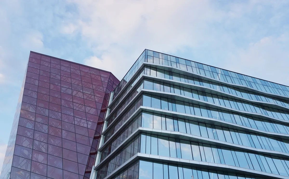 Corporate headquarters building exterior with modern glass architecture, viewed from street level under afternoon light, conveying corporate stability amid financial challenges