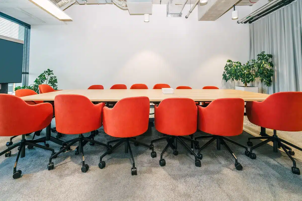 An empty corporate boardroom with a single chair facing a window overlooking a city skyline at dusk, conveying uncertainty and transition