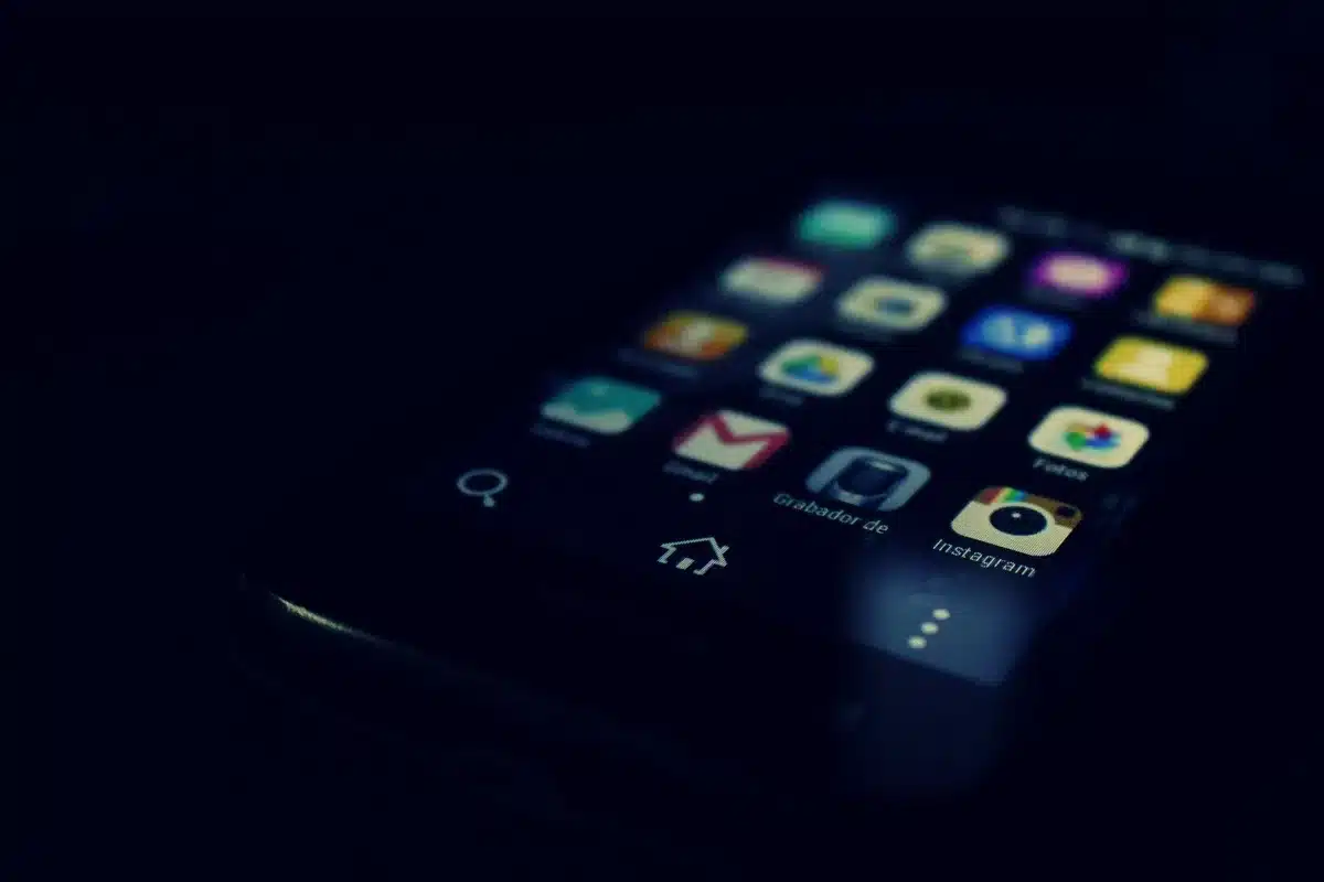 A smartphone screen displaying a donation interface with verified organization logos and relief fund information, hands hovering over the device, soft focus on the background