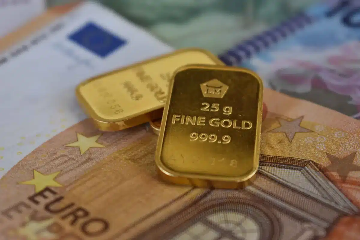 Gold bullion bars arranged on a trading desk with a declining Treasury yield chart in soft focus behind them