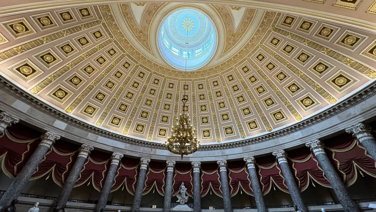 A formal hearing room with empty seats and microphones, symbolizing the institutional review process.