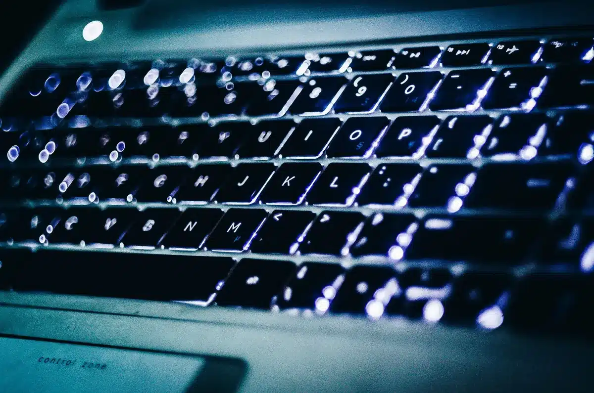 A close-up of a keyboard with search-related icons and warning symbols glowing on the keys, representing spam detection and filtering