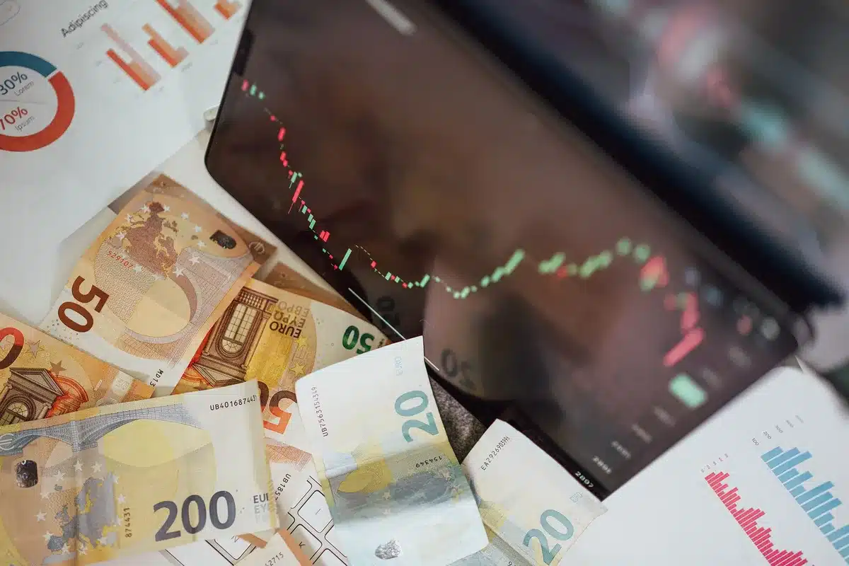 Hands holding financial documents with percentage gains visible, desk with calculator and stock charts, warm office lighting