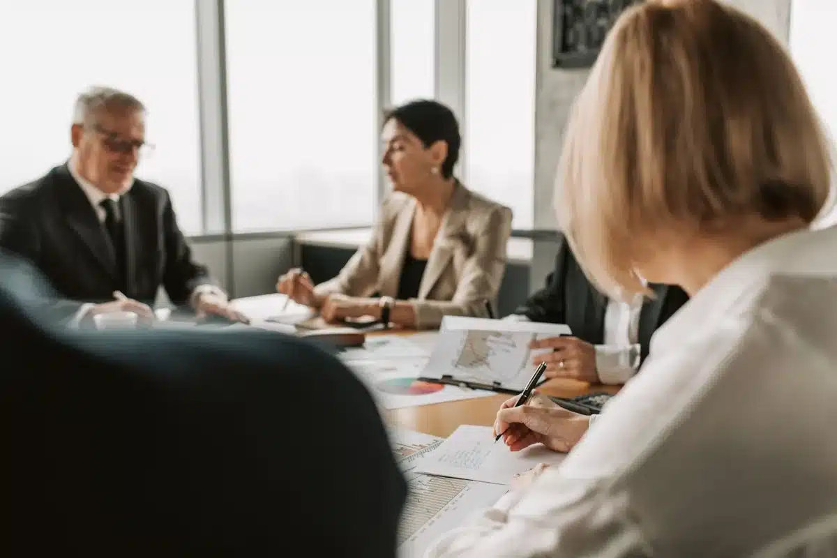 A modern conference room or investment boardroom with large windows overlooking a city skyline, a polished table with documents and laptops, morning sunlight streaming in, suggesting high-stakes business decisions and institutional capital.