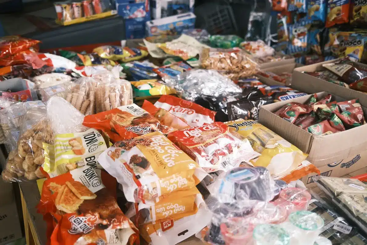 A grocery store shelf stocked with packaged foods of varying types, with focus on ingredient labels and product composition visible on packaging.