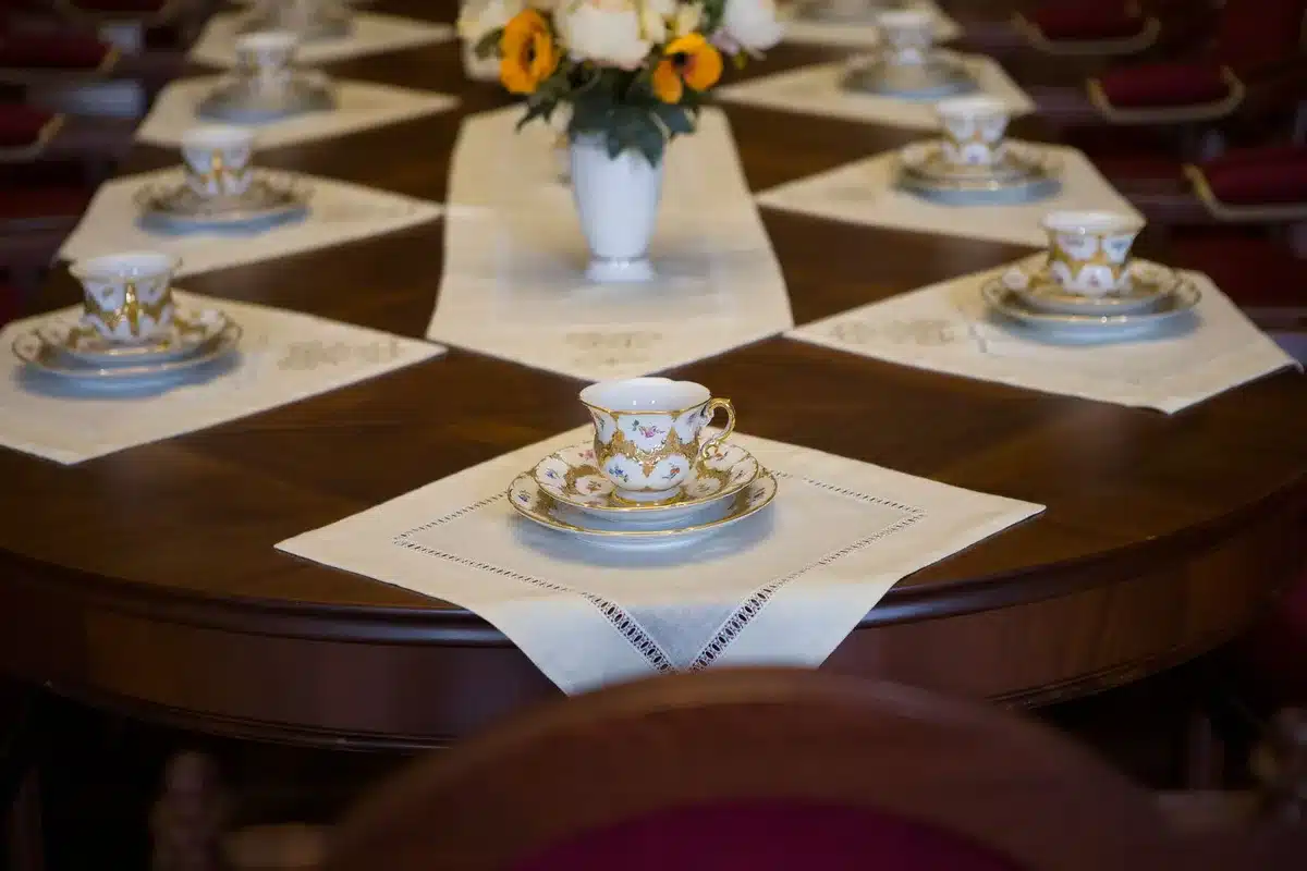 An empty diplomatic reception room with a single chair and formal setting, evoking the tension between two nations and the weight of formal diplomatic protocol.