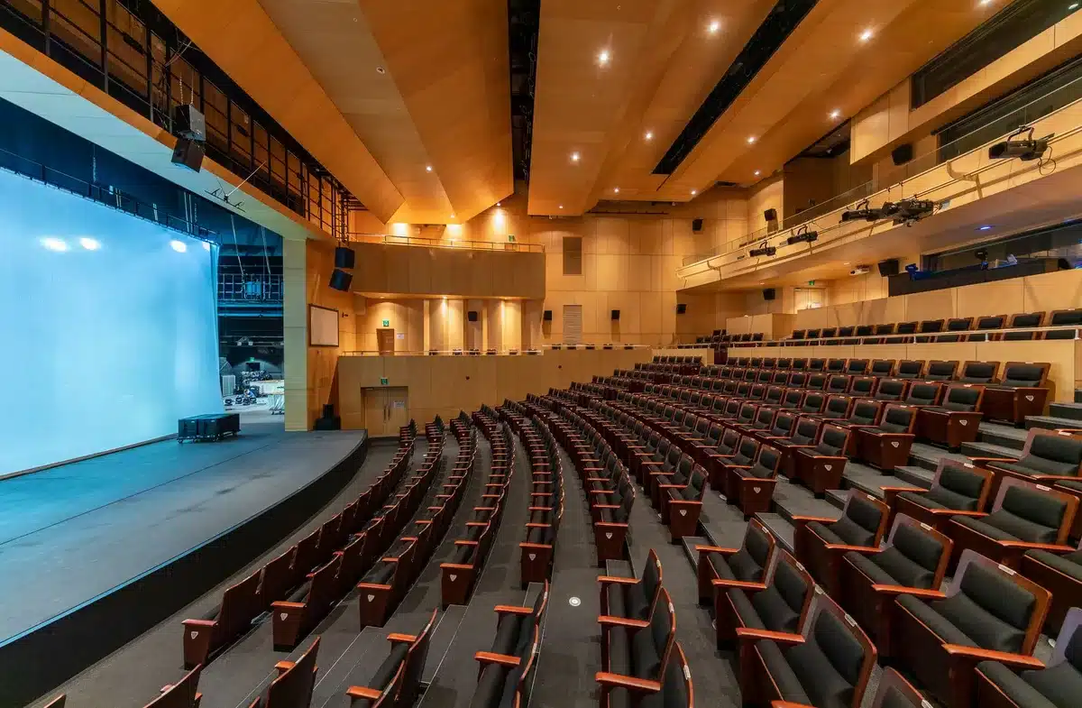 A Pentagon auditorium with rows of seats facing a podium, soft religious light and an American flag visible, conveying official government space