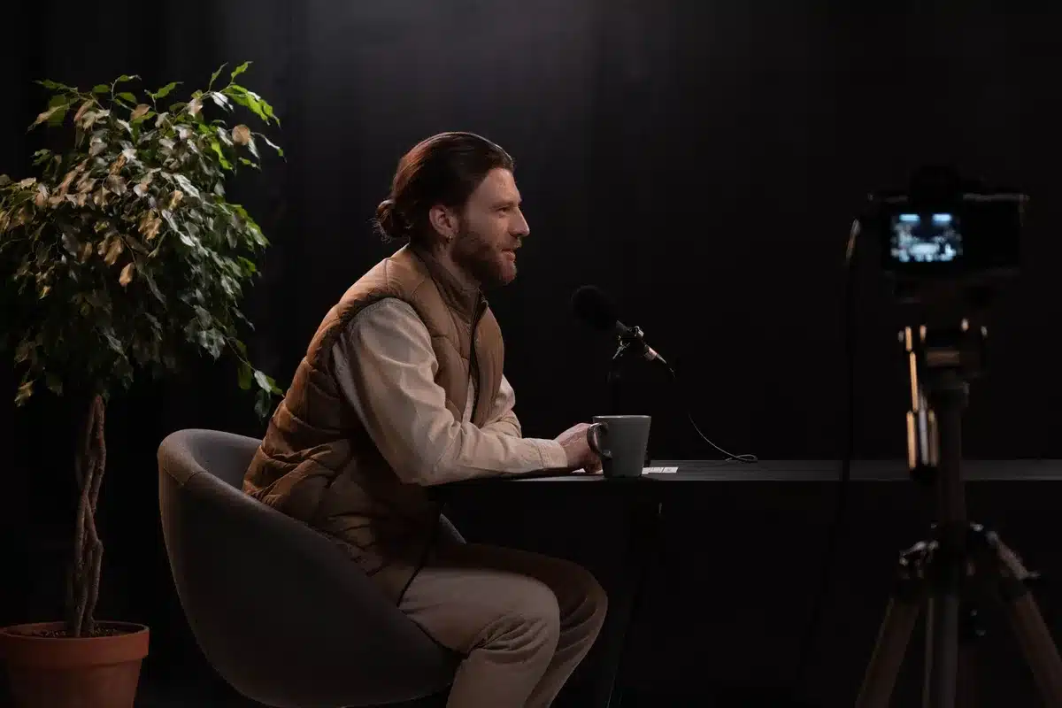 A television studio set with microphones and chairs arranged for an interview, soft lighting casting shadows across the empty stage, a sense of candid conversation space.