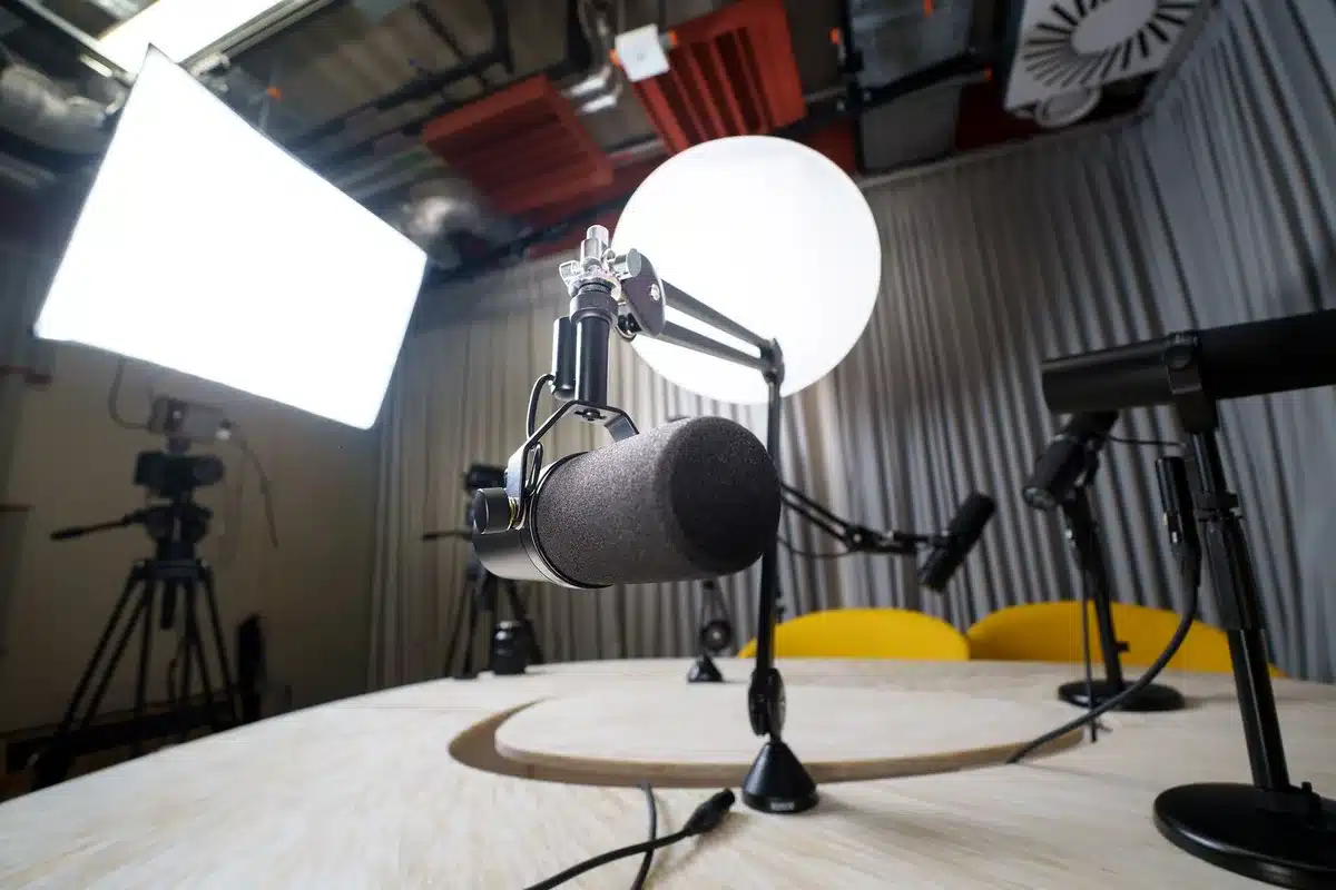Podcast studio with microphone and headphones on a desk, warm lighting casting shadows, suggesting an intimate conversation setting