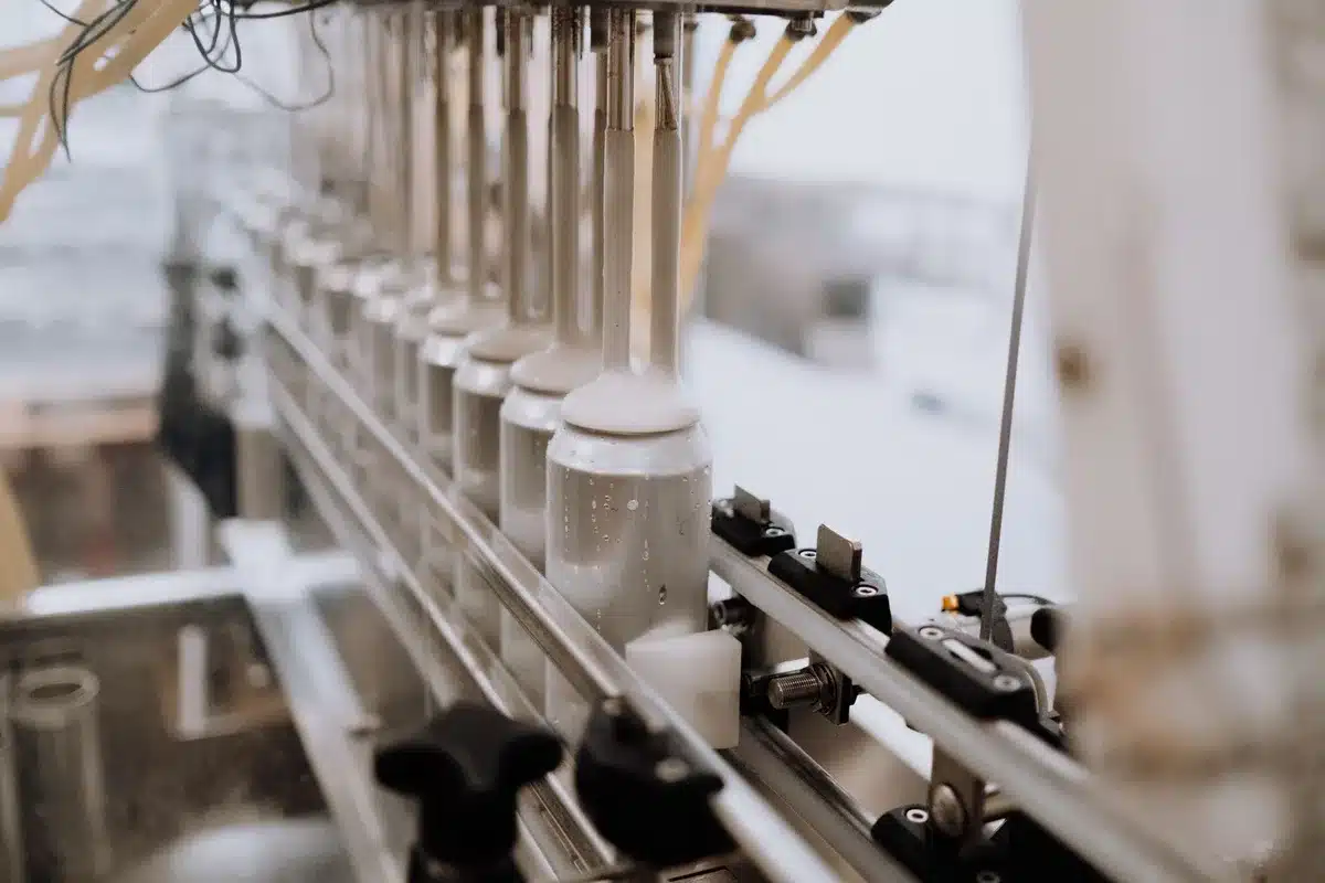 Production equipment and ice cream containers in a manufacturing facility, close-up focus on machinery.