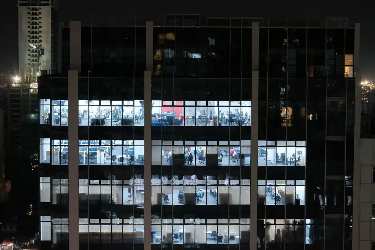 Corporate office building exterior with glass windows and modern architecture, morning light illuminating the facade.