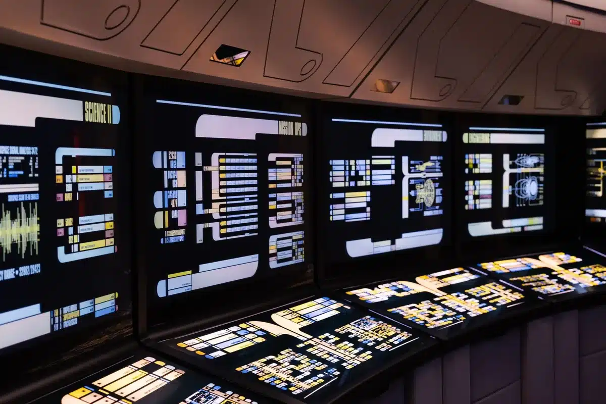 A modern data center facility entrance or control room with soft ambient lighting, monitors displaying system metrics and infrastructure status, a clean, organized technical environment conveying operational readiness and precision.