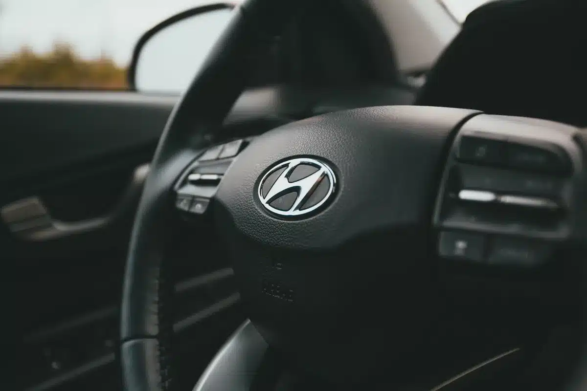 A close-up of a Tesla steering wheel with the voice control button highlighted, representing how drivers activate the Grok AI assistant while driving.