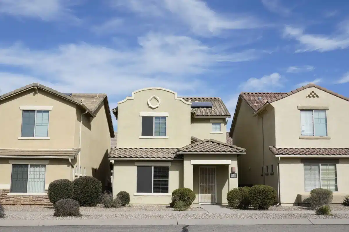 A modern suburban Phoenix landscape with upscale homes nestled against desert hills under bright Arizona sunlight, representing the affluent district communities