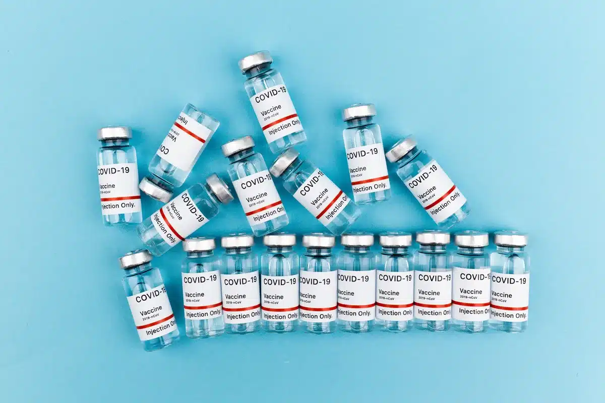 A medical examination room with vaccine bottles and syringes arranged on a sterile surface, clinical but neutral setting