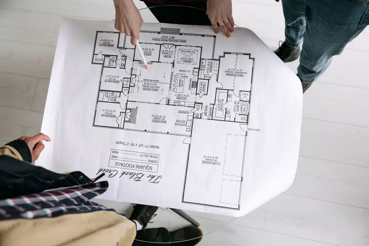 A blueprint or architectural rendering of residential housing development on a desk with calculator and pen, showing new construction plans