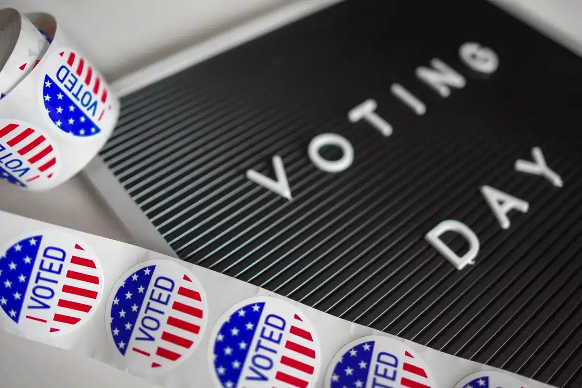 Multiple voting booths in a county election center, citizens filling out ballots, election officials monitoring, diverse age groups participating