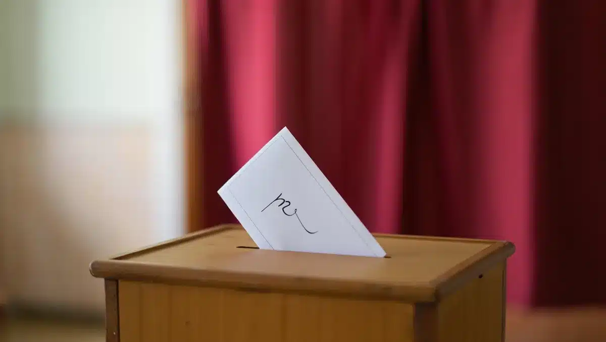 Ballot box with a "no" vote slip, voting booth curtain in soft focus behind, polling place interior | voting amendment ballot