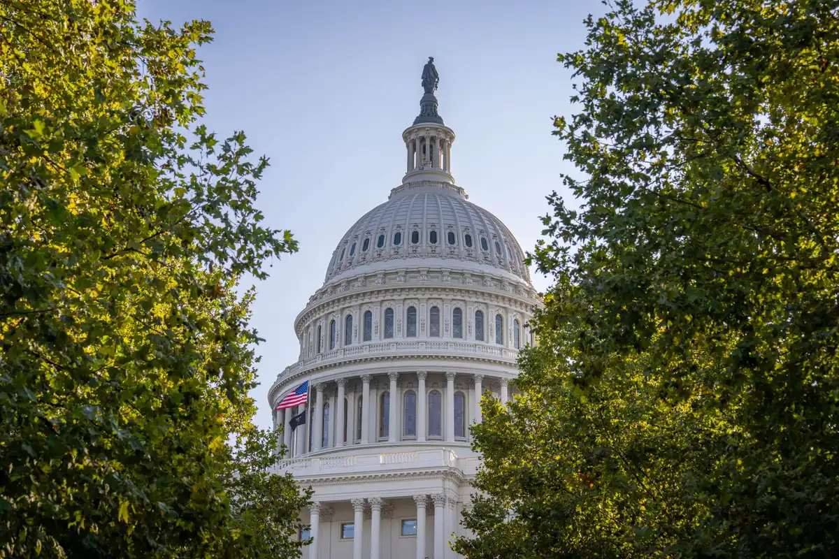 A historic Capitol building corridor with portraits and plaques honoring pioneering women legislators, soft natural light streaming through tall windows, conveying institutional legacy and achievement.