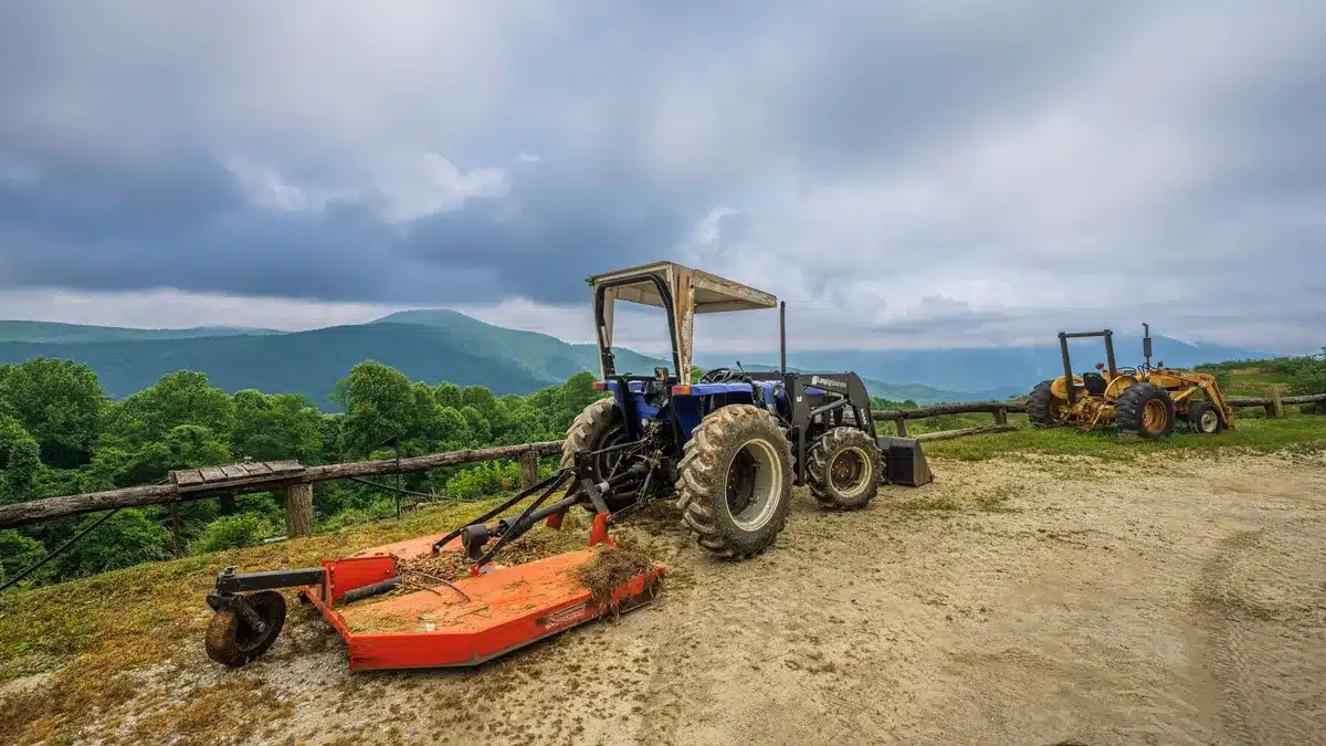 An agricultural equipment dealer lot with large farm machinery silhouetted against a rural sky, rows of tractors and combines, golden late-afternoon light