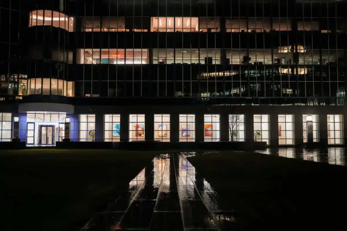 A modern office building with closed doors and empty parking lot on a holiday, desks visible through windows with no workers, conveying the business shutdown of a federal holiday