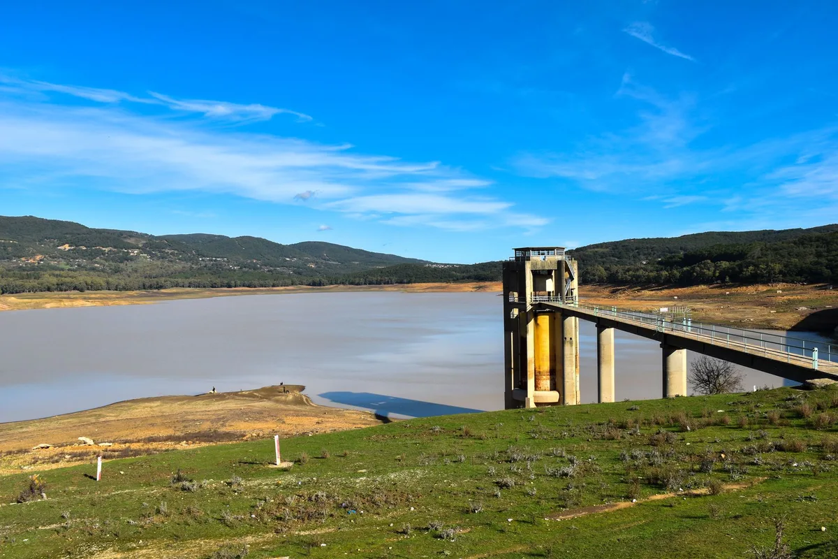A hydroelectric dam interior with turbines visible but water level visibly lower than normal, suggesting reduced power generation capacity